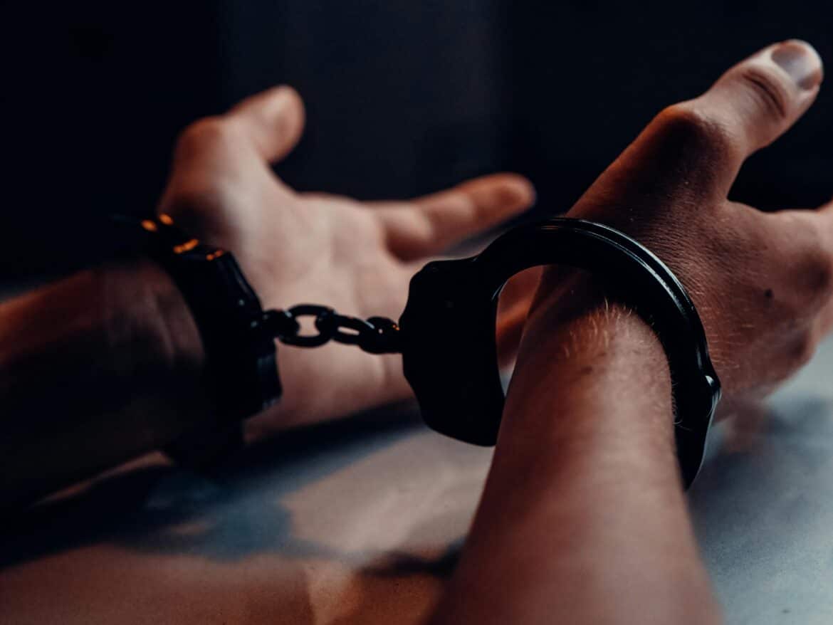 A person s hands on the table wearing handcuffs