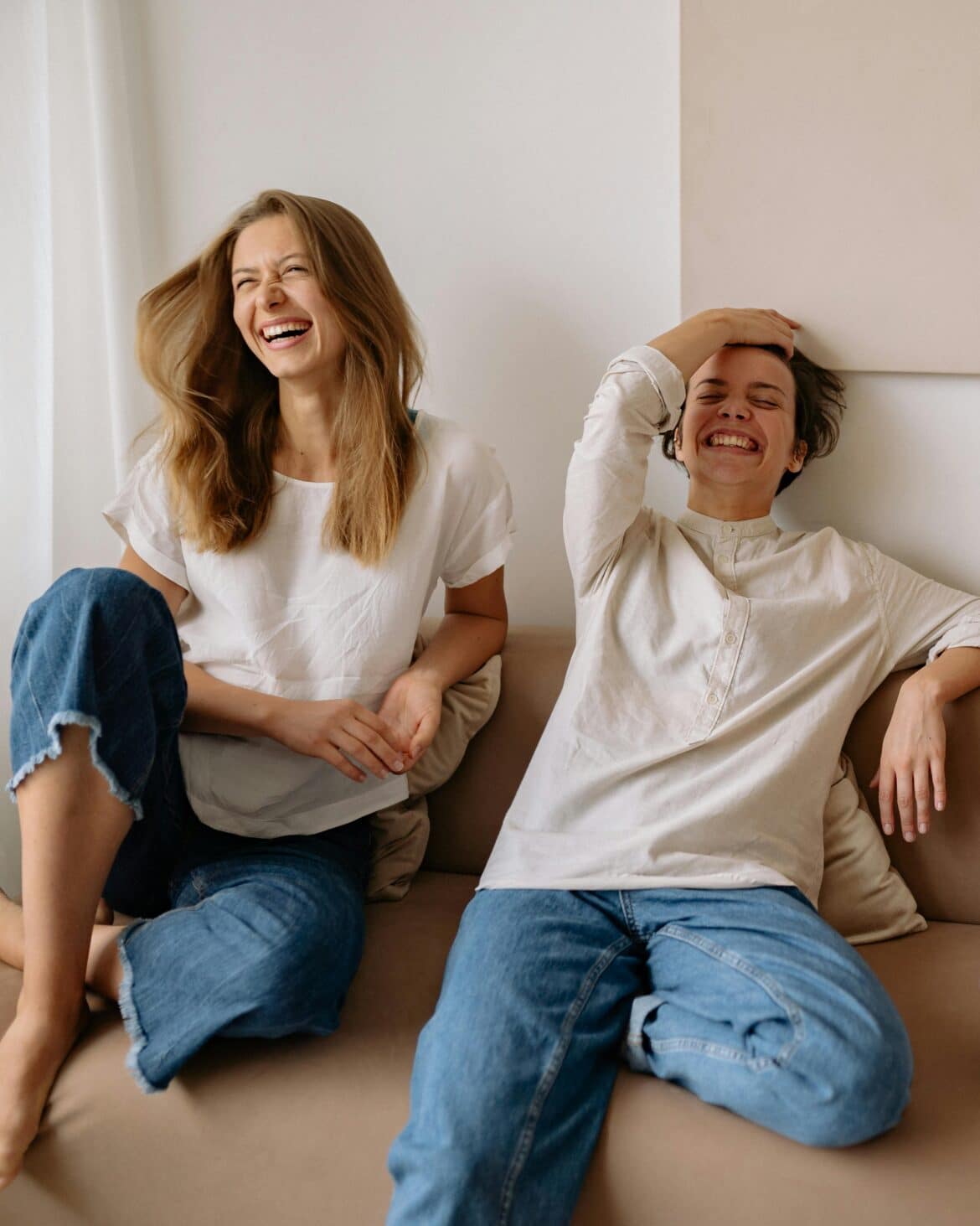 Woman in white crew neck t shirt sitting beside woman in white long sleeve shirt